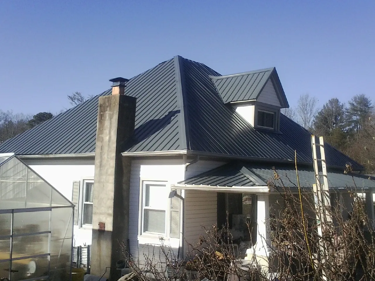 Dark blue standing seam metal roof on a white farmhouse with dormer — Slate & Tile Roof Repair by Roofing Brothers in Mantua