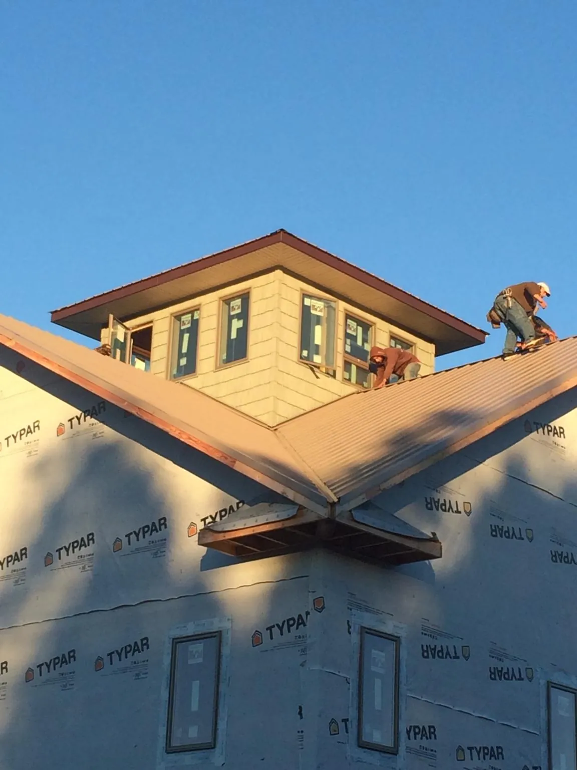 Roofers working around a rooftop cupola on a new metal roof at sunset — Roof Waterproofing in Mantua by Roofing Brothers